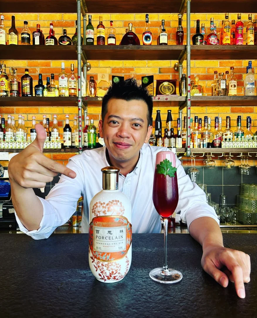 A bartender presenting Porcelain Gin and a cocktail.